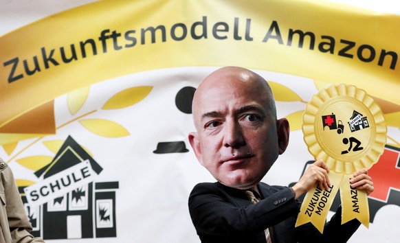 epa06689715 A protester wears a Jeff Bezos mask as he joins a protest against the working conditions at Amazon near the Axel Springer Verlag building in Berlin, Germany, 24 April 2018. Amazon CEO Jeff ...