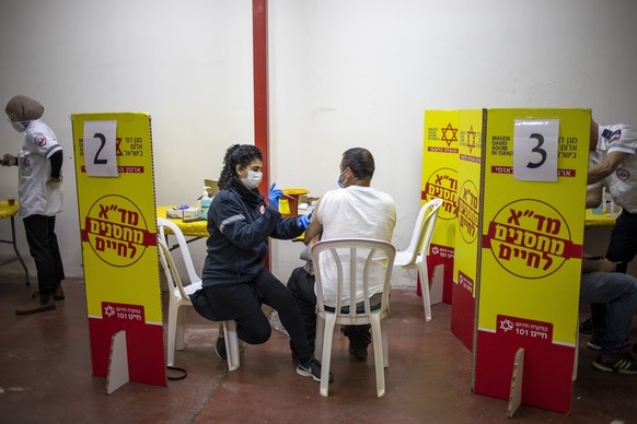 Palestinians who work in Israel receive their first dose of the Moderna COVID-19 vaccine at a coronavirus vaccination center set up in a factory in the joint Israeli-Palestinian industrial zone of Bar ...