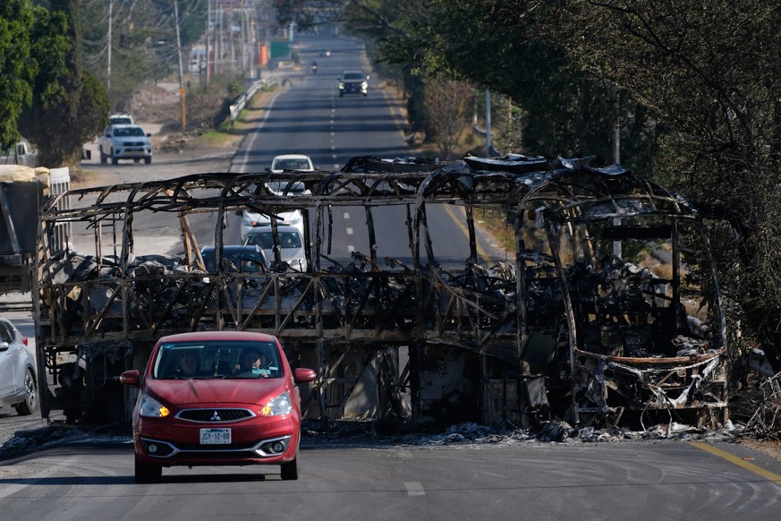 Vehicles drive past a charred bus the day after the Mexican army killed Jalisco New Generation Cartel leader Nemesio Oseguera Cervantes, known as "El Mencho," in Guadalajara, Mexico, Monday, ...