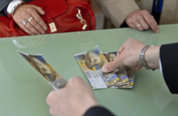 Clients are withdrawing cash at the counter of the branch bank of Raiffeisen in Appenzell, Switzerland. Pictured on May 4, 2012. (KEYSTONE/Martin Ruetschi) [STAGED PICTURE/SYMBOLIC IMAGE]

Kunden bezi ...