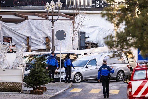 A hearse car drives as Police officers inspect the area where a unidentified origin fire broke out at the Le Constellation bar and lounge leaving people dead and injured, during New Years celebration ...