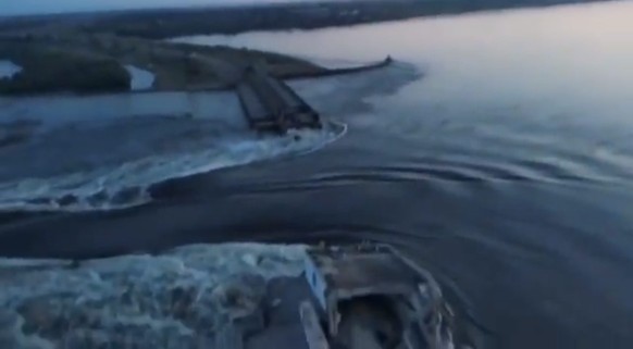epa10675812 A still image taken from a handout video made available by the telegram account of the President of Ukraine, Volodymyr Zelensky on 06 June 2023 of water running through a breakthrough in t ...