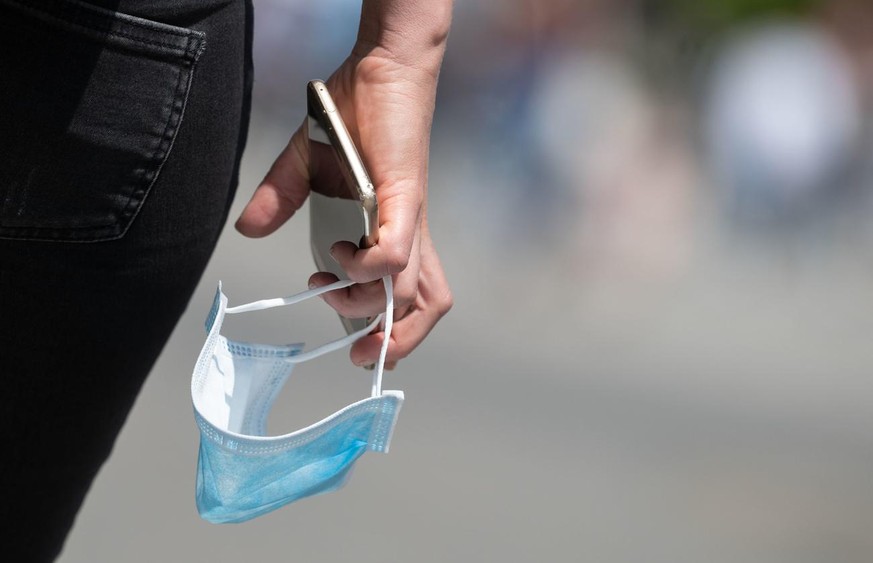 27.05.2020, Baden-Württemberg, Stuttgart: Eine Passantin hält auf der Königstraße einen Mund-Nasen-Schutz und ein Smartphone in der Hand. Die CDU-Spitzenkandidatin für die Landtagswahl in Baden-Württe ...