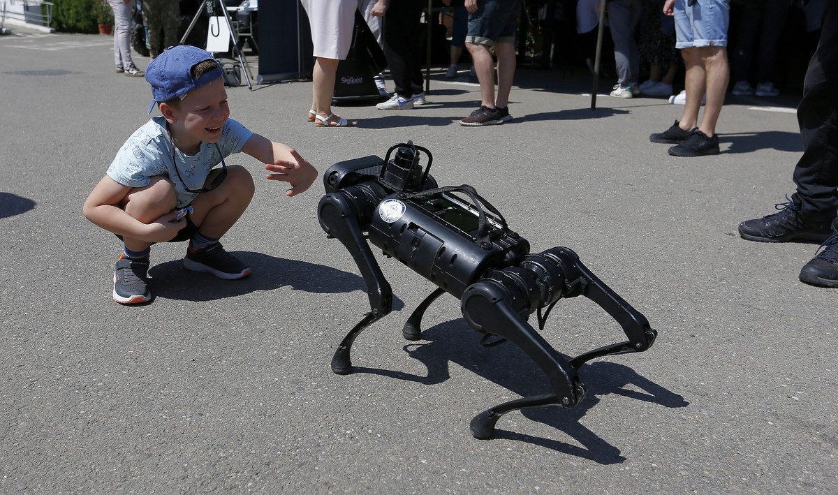 epa11381959 Romanian boy Eduard, 6, assisted by his father Vlad (not pictured), interacts with a dog robot for observing hostile spaces, that belongs to the Romanian Intelligence Service (SRI), during ...