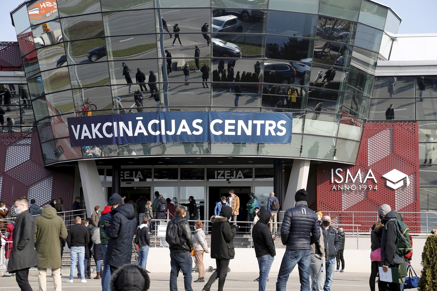 epa09138785 People wait in a long queue for a dose of vaccine against COVID-19 outside the mass vaccination center which is set-up in the multifunctional business Atta Center in Riga, Latvia, 16 April ...