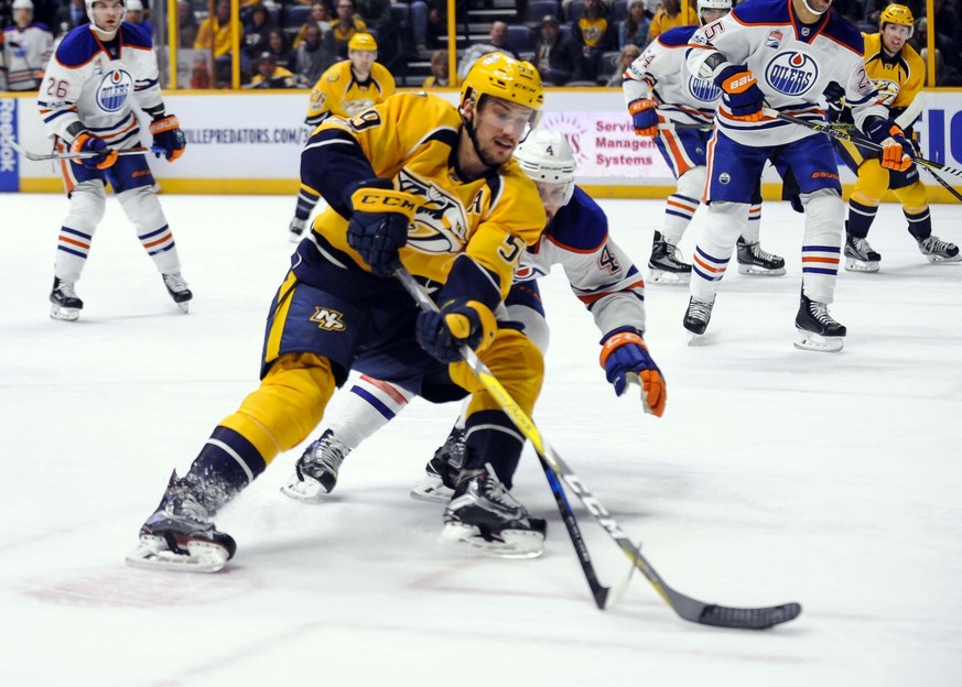 Feb 26, 2017; Nashville, TN, USA; Nashville Predators defenseman Roman Josi (59) fights for the puck with Edmonton Oilers defenseman Kris Russell (4) during the first period at Bridgestone Arena. Mand ...