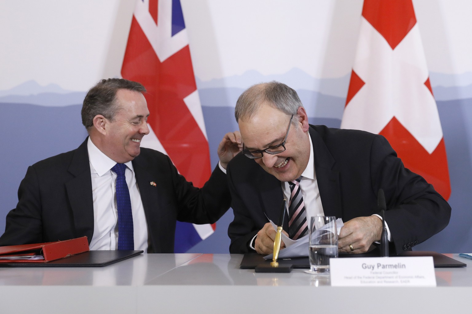 Swiss Federal Councillor Guy Parmelin, right, and British Secretary of State for International Trade Liam Fox, left, react after signing a trade agreement in Bern, Switzerland, Monday, Feb. 11, 2019.  ...