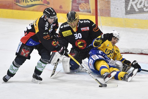 Berns David Jobin, links, und SC Bern Torhueter Leonardo Genoni, Mitte, im Duell gegen Davos&#039; Andres Ambuehl im Eishockey National League A Spiel zwischen dem SC Bern und dem HC Davos, am Freitag ...