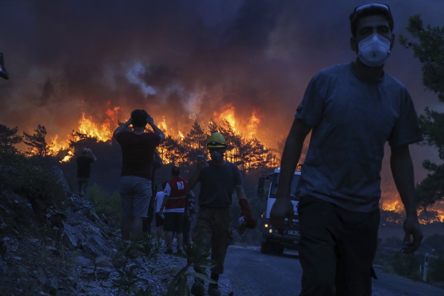 People watch a wildfire near Akcayaka village in Milas, Mugla in southwest Turkey, Thursday, Aug. 5, 2021. A wildfire that reached the compound of a coal-fueled power plant in southwest Turkey and for ...