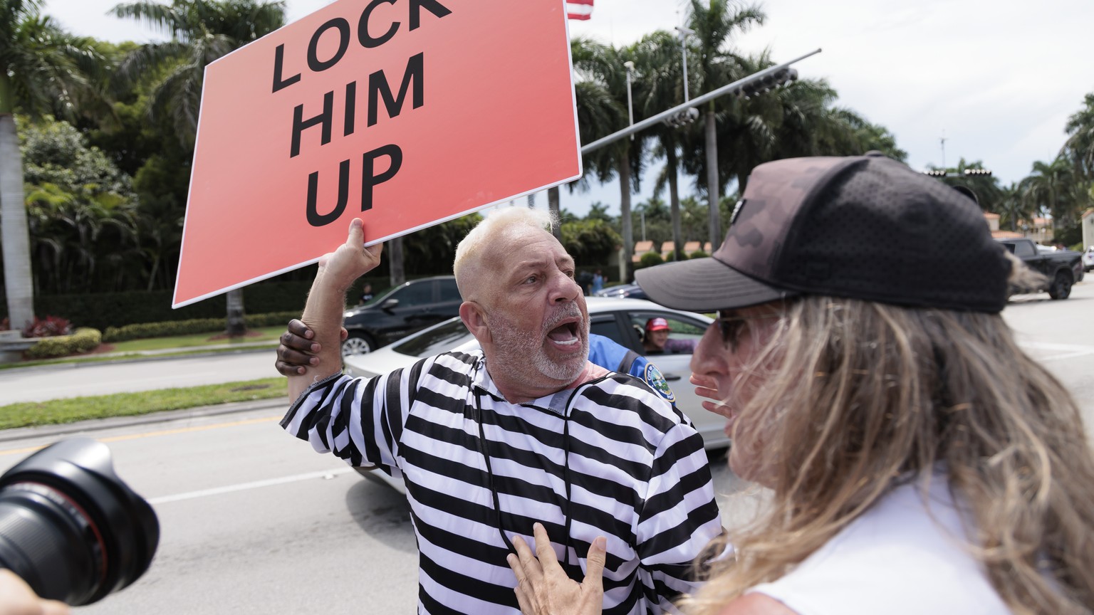 epa10687557 Anti-Trump protestor Domenic Santana (L) yells at supporters of former President Donald Trump near the entrance to the Trump National Doral Miami golf course in Doral, Florida, USA, 12 Jun ...
