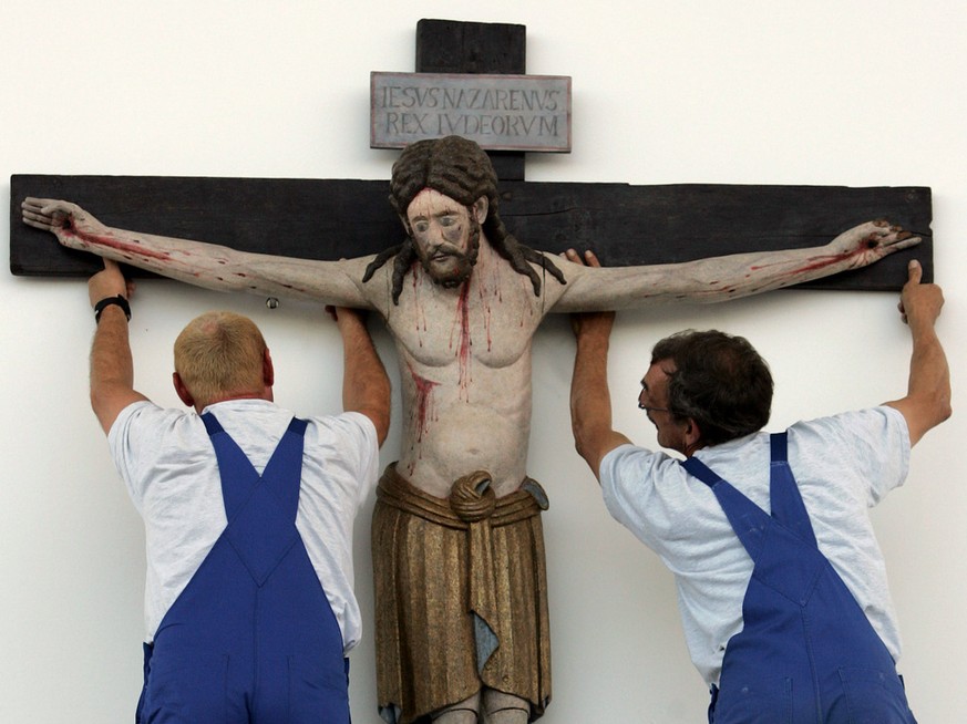 Workers suspend the 1100-year-old crucifix from the church of the village of Enghausen, Bavaria, above the altar on the fair grounds in Munich, southern Germany, Thursday, Sept. 7, 2006, where pope Be ...