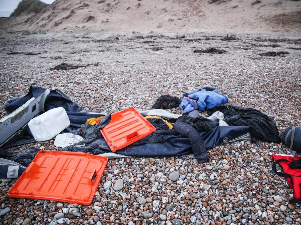 epa09602082 Remains of damaged migrants' inflatable boat and a sleeping bag left by migrants on the beach near Wimereux, France, 25 November 2021. At least 27 migrants have died and two more were ...