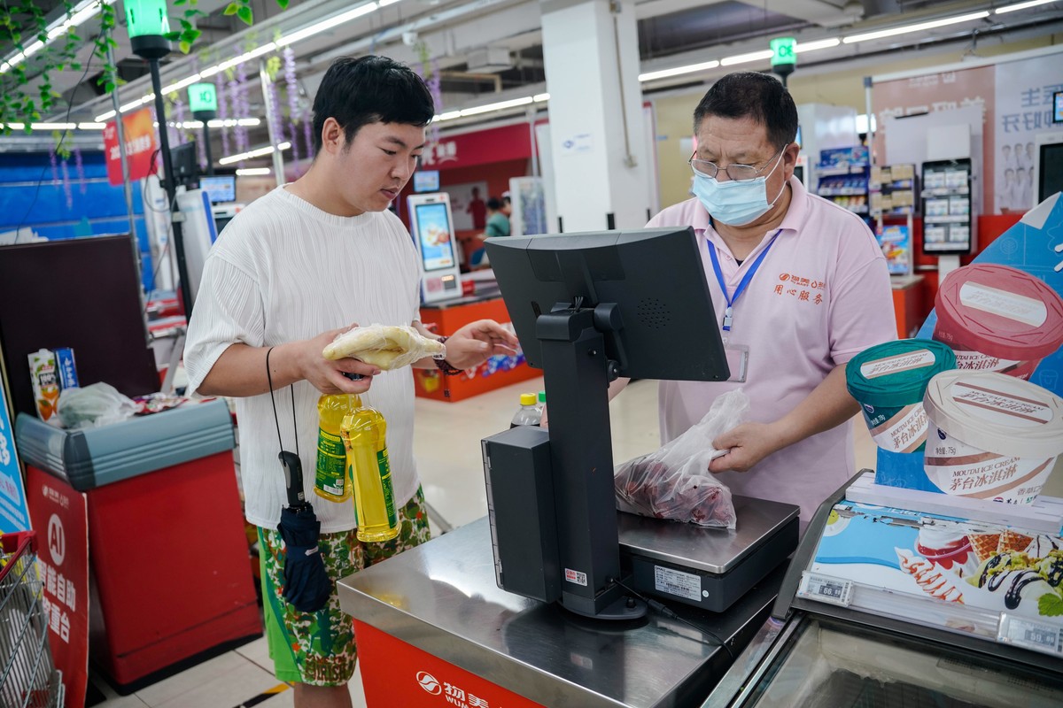 epa10742966 A staff weighs food for a customer in a supermarket in Beijing, China, 13 July 2023. China's trade surplus was at 65.81 billion dollars in May 2023, declined from 78.40 billion in the ...