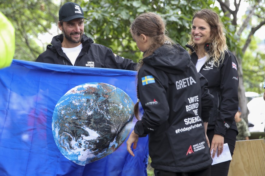Boris Herrmann, left, the captain of the zero-emissions yacht, the Malizia II, presents Greta Thunberg, a 16-year-old Swedish climate activist, with a flag with an image of the earth after they arrive ...