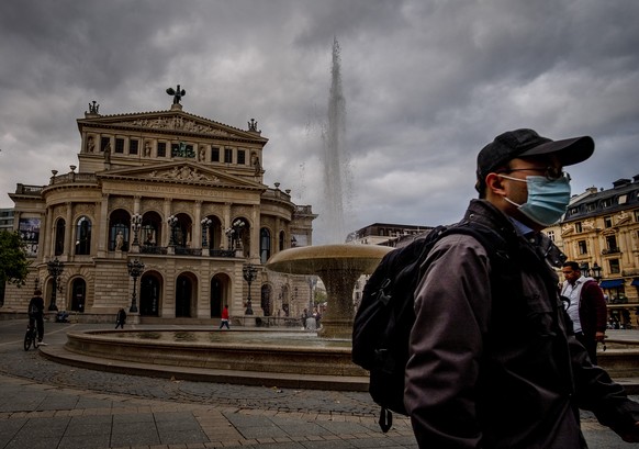 A man wears a face mask as he walks past the Old Opera in Frankfurt, Germany, Monday, Sept. 28, 2020. (AP Photo/Michael Probst)