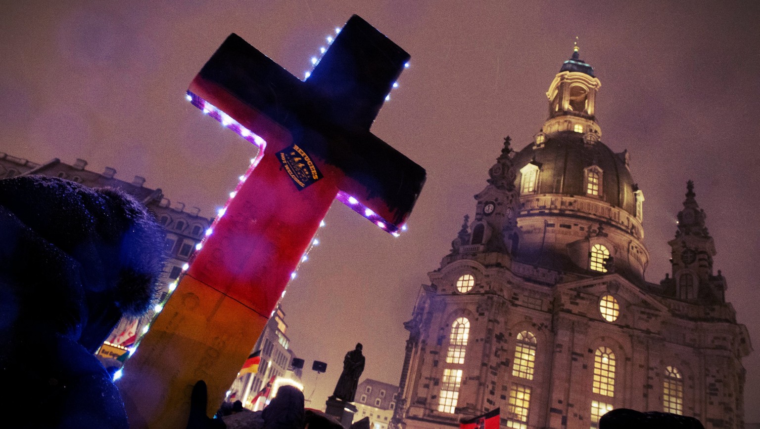 epa05187762 Supporters of the xenophobic and anti-islamic Pegida movement demonstrating with a cross in front of the Frauenkirche (Women Church) in Dresden, Germany, 29 February 2016. The &#039;Patrio ...