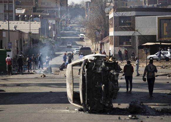 epa09336832 A burned car is seen at a road block in downtown Johannesburg, South Africa, 11 July 2021. President Zuma was arrested on Tuesday 06 July and sentenced to 15 months in prison for contempt  ...