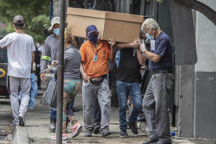 Cemetery workers carry the remains of a person in a cardboard coffin for burial at the General Cemetery in Guayaquil, Ecuador, Monday, April 6, 2020. Guayaquil, a normally bustling city that has becom ...