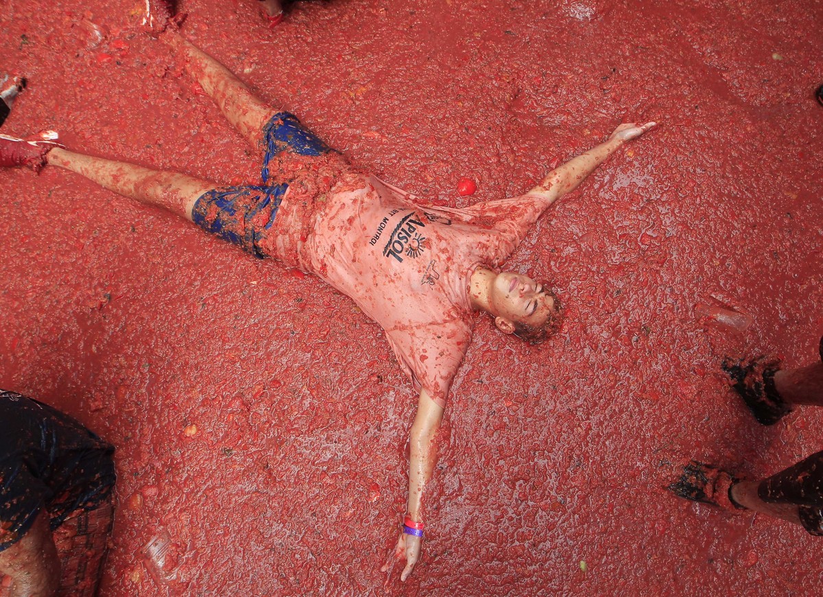 A men lies in a puddle of squashed tomatoes during the annual "Tomatina", tomato fight fiesta, in the village of Bunol, 50 kilometers outside Valencia, Spain, Wednesday, Aug. 30, 2017. The s ...