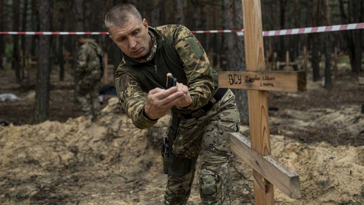Oleg Kotenko, the Commissioner for Issues of Missing Persons under Special Circumstances uses his smartphone to film the grave a Ukrainian soldier in the recently retaken area of Izium, Ukraine, Thurs ...