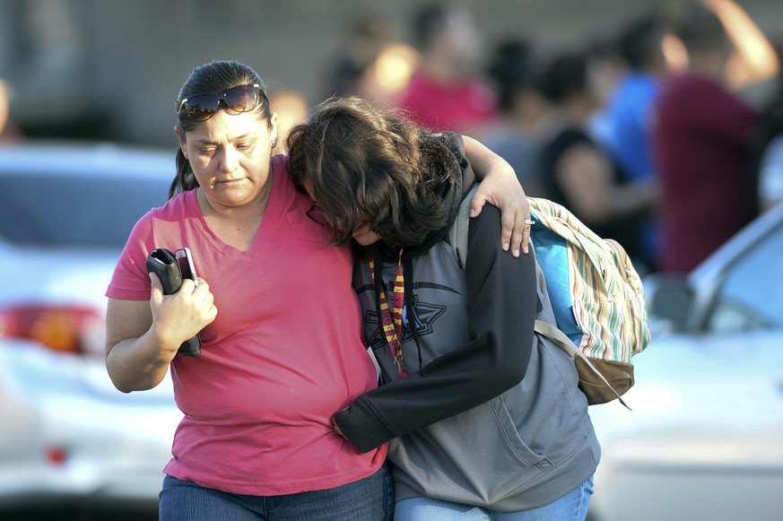 A parent picks up her daughter at Slauson Middle School that was on lockdown as Azusa police and other agencies respond to a shooting near Fourth Street and Orange Avenue in Azusa, Calif. on Tuesday,  ...