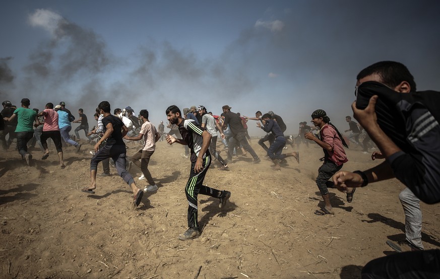 epa06728746 Palestinians protesters run for cover from Israeli tear-gas during clashes near the border with Israel in the east of Gaza City, 11 May 2018. Reports state that one protester was killed an ...