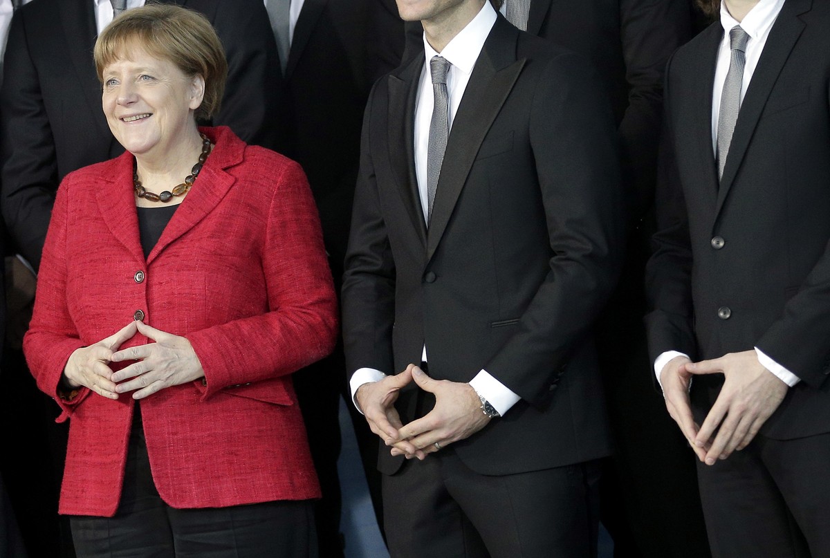 FILE - In this March 9, 2016 file photo Chancellor Angela Merkel, left, and team members make Merkel's trademark gesture as they pose for the media during a reception for the German National Hand ...