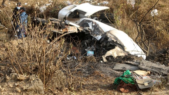 epa10406668 Belongings (R, front) next to the wreckage at the crash site of a Yeti Airlines ATR72 aircraft in Pokhara, central Nepal, 15 January 2023. A Yeti Airlines ATR72 aircraft carrying 72 people ...