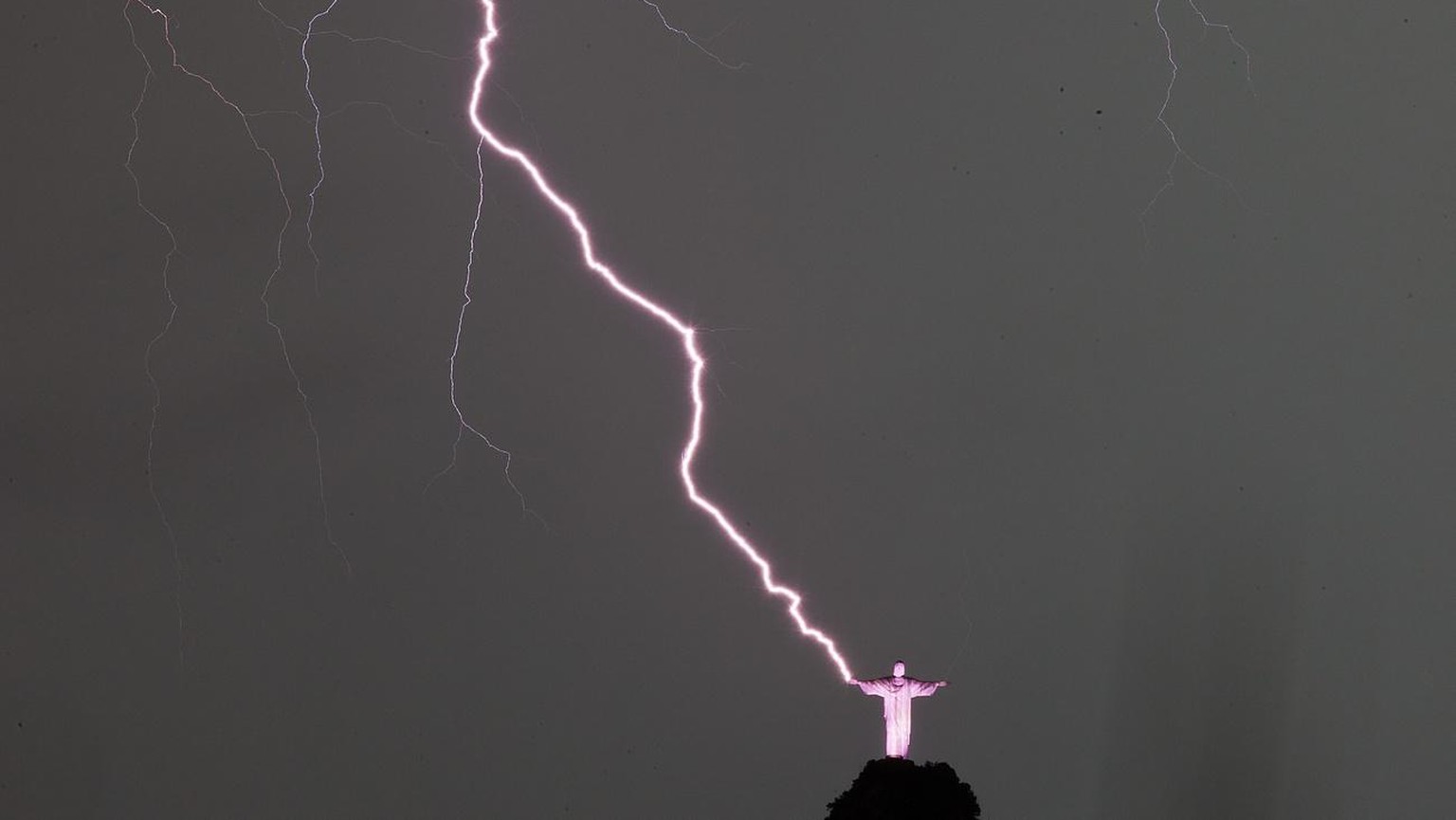 epa04025352 View of lightning that strikes next to the statue Christ the Redeemer in Rio de Janeiro, Brazil, 16 January 2014. The city has suffered a strong storm that left neighborhoods without power ...