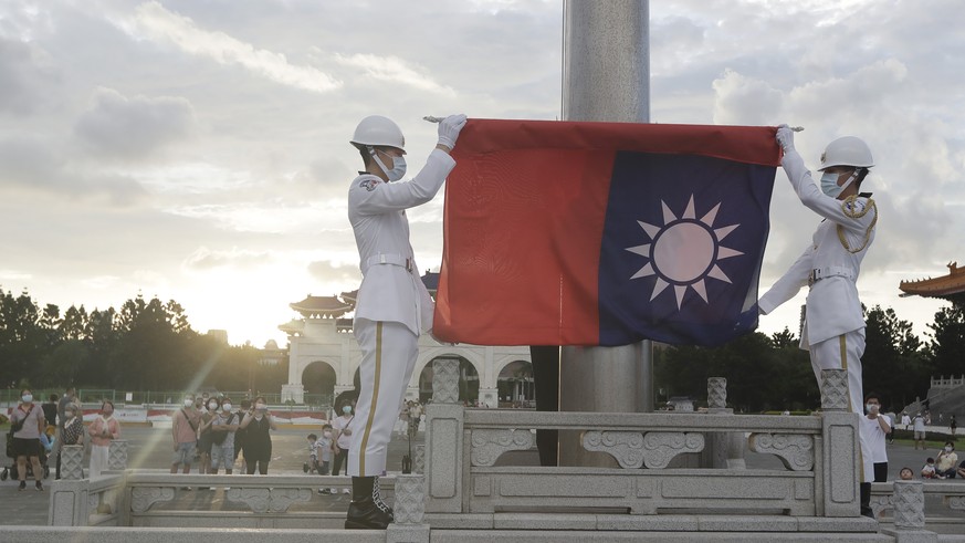 Two soldiers fold the national flag during the daily flag ceremony on the Liberty Square of Chiang Kai-shek Memorial Hall in Taipei, Taiwan, Saturday, July 30, 2022. (AP Photo/Chiang Ying-ying)