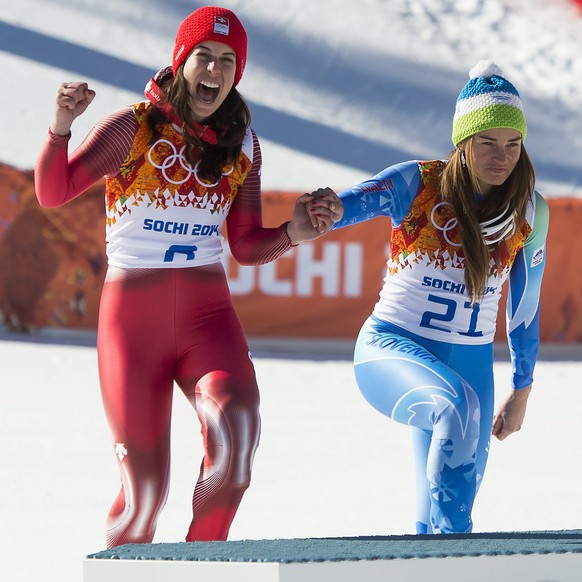 epa04071105 Joint gold medal winners Dominique Gisin (L) of Switzerland and Tina Maze of Slovenia enter the podium for the flower ceremony for the Women's Downhill race at the Rosa Khutor Alpine  ...