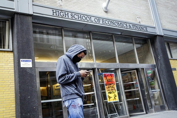 FILE - In this March 16, 2020, file photo, a pedestrian wears a face mask while standing outside the High School of Economics &amp; Finance, closed due to coronavirus concerns, in New York. New York G ...