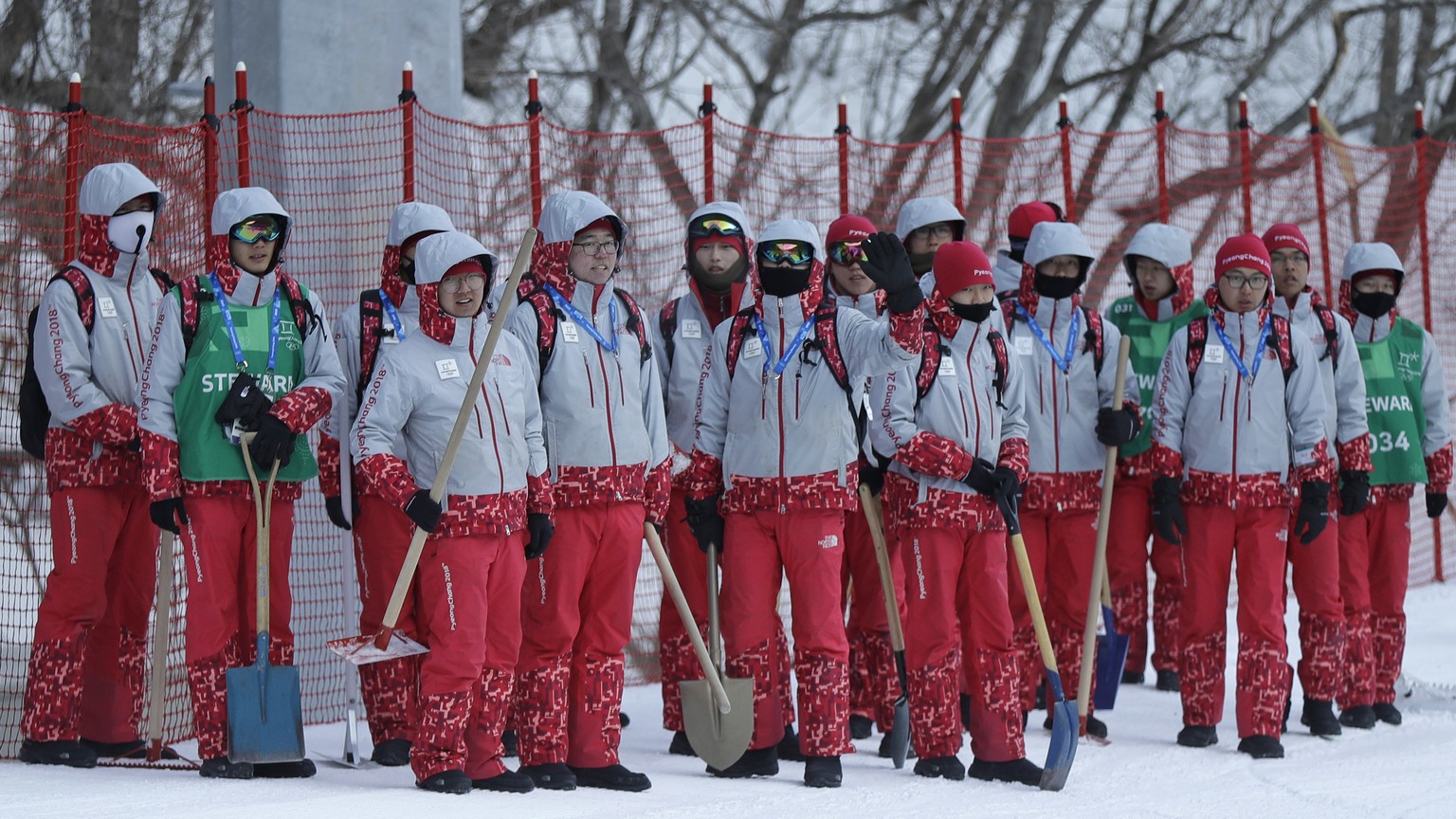 Volunteers stand near the finish area after the men&#039;s downhill was postponed due to high winds at the 2018 Winter Olympics in Jeongseon, South Korea, Sunday, Feb. 11, 2018. (AP Photo/Luca Bruno)