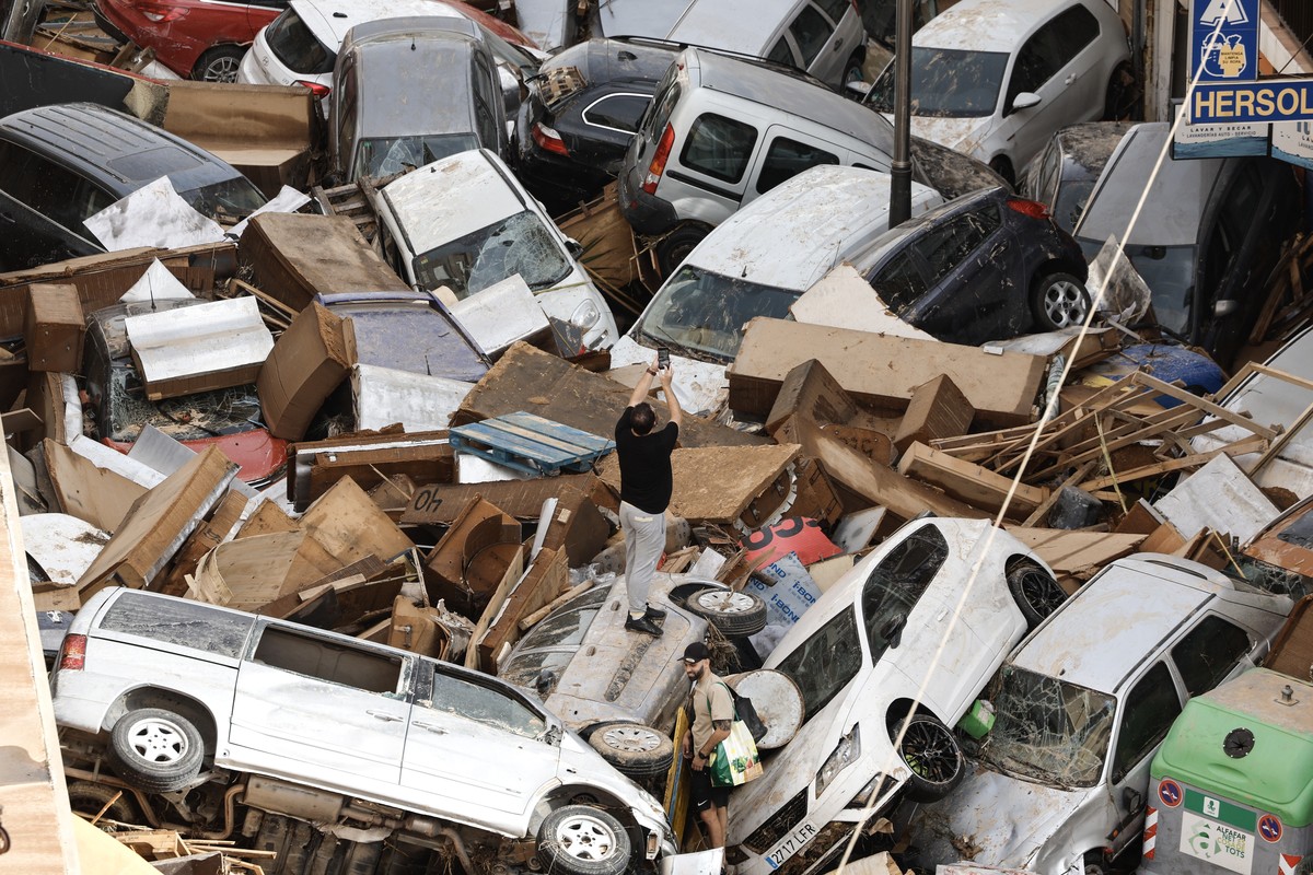 epa11692692 A resident takes pictures among damaged vehicles piled up in the flood-hit municipality of Sedavi, in the province of Valencia, eastern Spain, 30 October 2024. The intense rainfall impacti ...