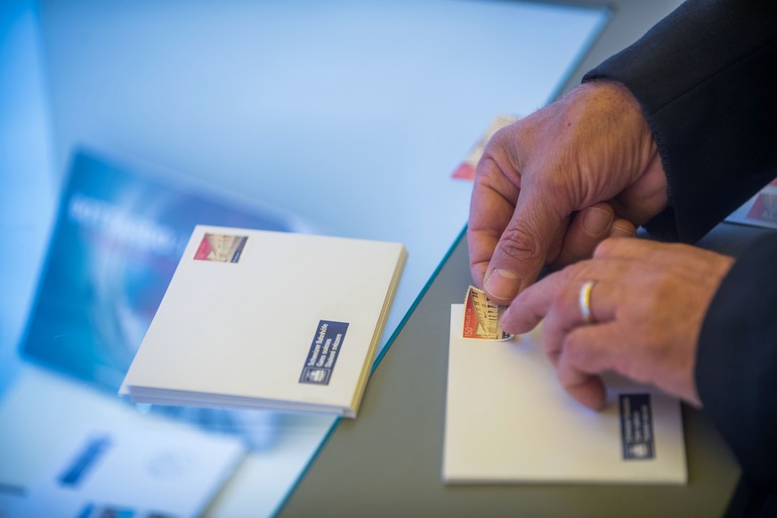 Eine Person klebt eine Briefmarke mit dem Bahnhof Bellinzona, aus der Dauermarkenserie Schweizer Bahnhoefe der Schweizerischen Post, auf ein Couvert waehrend den Feierlichkeiten und dem Volksfest zur  ...