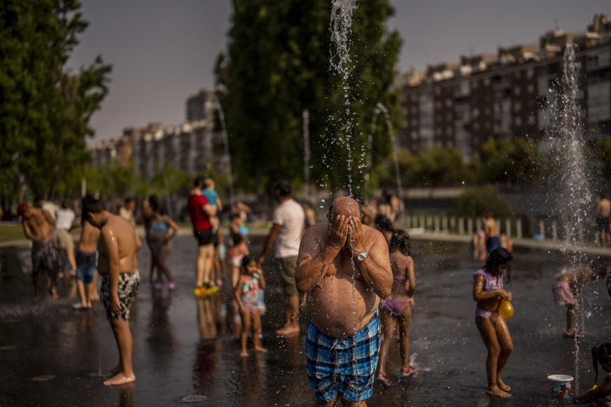 People cool off at an urban beach in Madrid Rio park during a heat wave in Madrid on July 13, 2022. (AP Photo/Manu Fernandez)