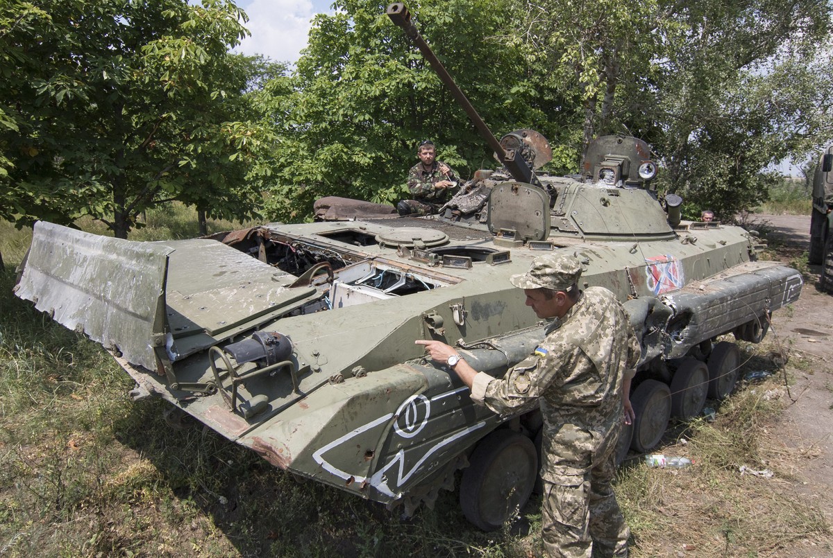 epa04851968 Volunteers of the Ukrainian 'Donbass' battalion examine a damaged armored military vehicle, which they claim belonged to pro-Russian separatists and recently captured by 'Do ...