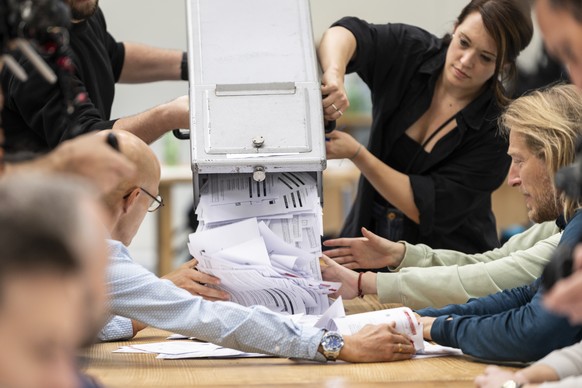 Isabelle Schorer, Mitglied des staendigen Stimmausschusses der Stadt Bern, kippt Stimmausweise aus einer Wahlurne auf den Zaehltisch, am Tag der Eidgenoessischen Wahlen, am Sonntag, 22. Oktober 2023 i ...