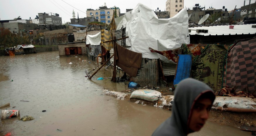 A Palestinian walks through flood water following heavy rain in a neighbourhood in the northern Gaza Strip February 16, 2017. REUTERS/Mohammed Salem