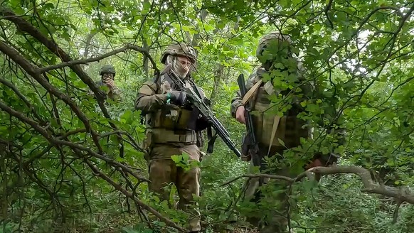 In this photo taken from video released by the Russian Defense Ministry Press Service on Wednesday, June 12, 2024, Russian soldiers of the reconnaissance unit walk though a forest in an undisclosed lo ...