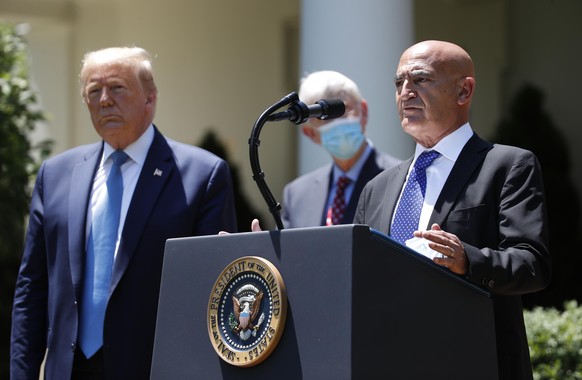 President Donald Trump, left, listens as Moncef Slaoui, a former GlaxoSmithKline executive, speaks about the coronavirus in the Rose Garden of the White House, Friday, May 15, 2020, in Washington. (AP ...