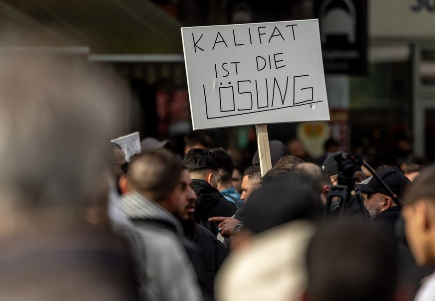 27.04.2024, Hamburg: Teilnehmer einer Islamisten-Demo halten ein Plakat mit der Aufschrift ·Kalifat ist die Lösung· in die Höhe. Foto: Axel Heimken/dpa +++ dpa-Bildfunk +++ (KEYSTONE/DPA/Axel Heimken)