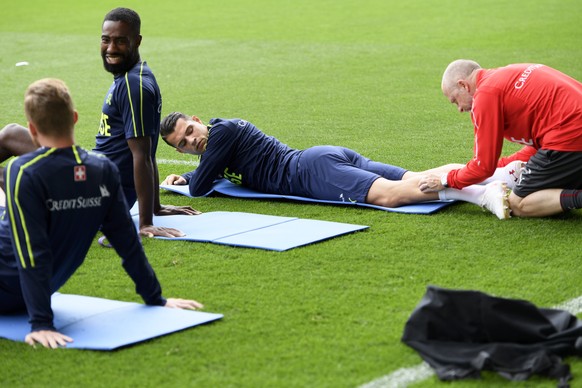 Switzerland&#039;s midfielder Granit Xhaka, center, is warming up by physiotherapists next to Johan Djourou , left, before a training session on the eve of an international friendly soccer match betwe ...