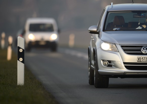 ARCHIV - Une voiture roule en plein jour avec ses phares allumes sur une route cantonale vaudoise ce mercredi 4 decembre 2013 a Daillens, Vaud. Une modification de la loi sur la circulation routiere q ...
