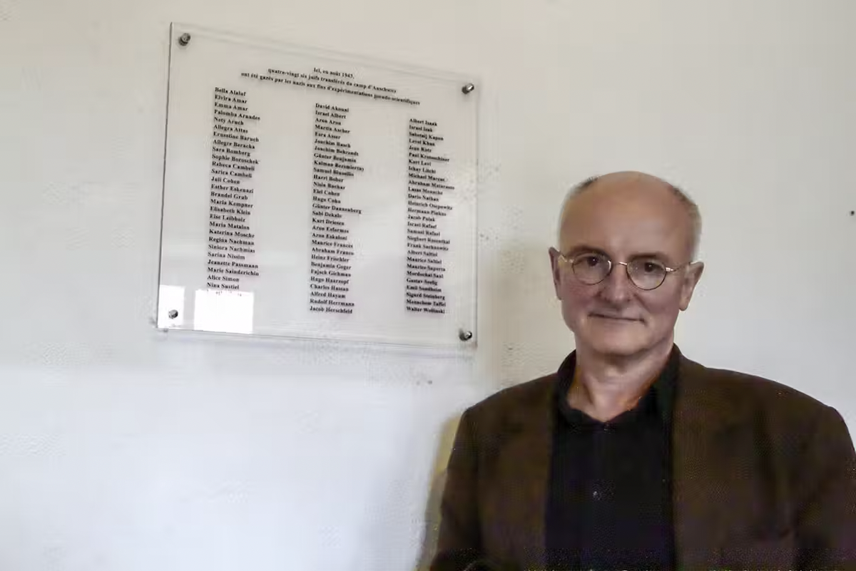 Hans-Joachim Lang devant la plaque commémorative comportant les noms des 86 victimes au camp de concentration de Natzweiler-Struthof, avril 2013.