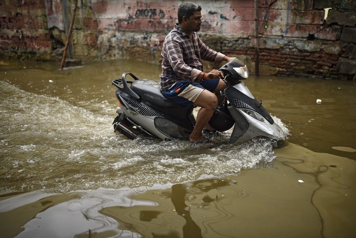 epa10281577 A man rides a scooter through a flooded street following heavy rainfall, in Chennai, India, 02 November 2022. The Indian Meteorological Department (IMD) predicts heavy rains and thundersto ...