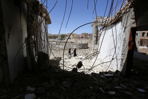 epa07463202 Yemeni women walk past a building allegedly destroyed by a previous Saudi-led airstrike, on the fourth anniversary of the Saudi-led military campaign on Yemen, in Sana&#039;a, Yemen, 25 Ma ...