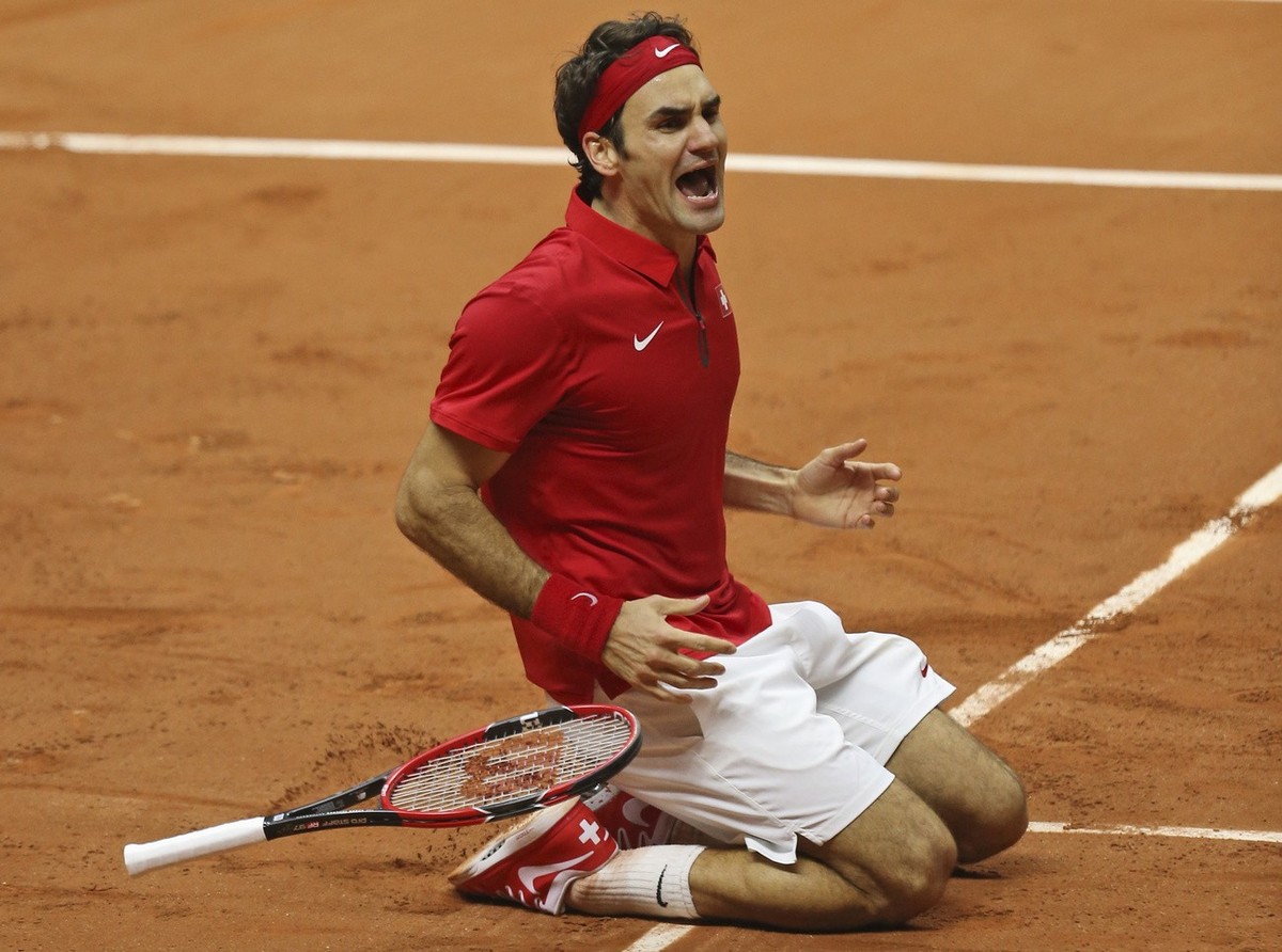 Switzerland's Roger Federer falls to the clay after defeating France's Richard Gasquet and winning the Davis Cup final between France and Switzerland at Stade Pierre Mauroy in Lille, norther ...