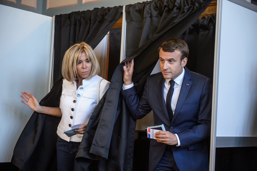 epa06022250 French President Emmanuel Macron (R) with his wife Brigitte Trogneux (L) cast their ballot at their polling station in the first round of the French legislatives elections in Le Touquet, n ...