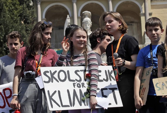 Swedish teenager and environmental activist Greta Thunberg waves as she holds a sign with writing reading in Swedish &quot;School strike for the climate&quot; during a Fridays for Future rally demandi ...